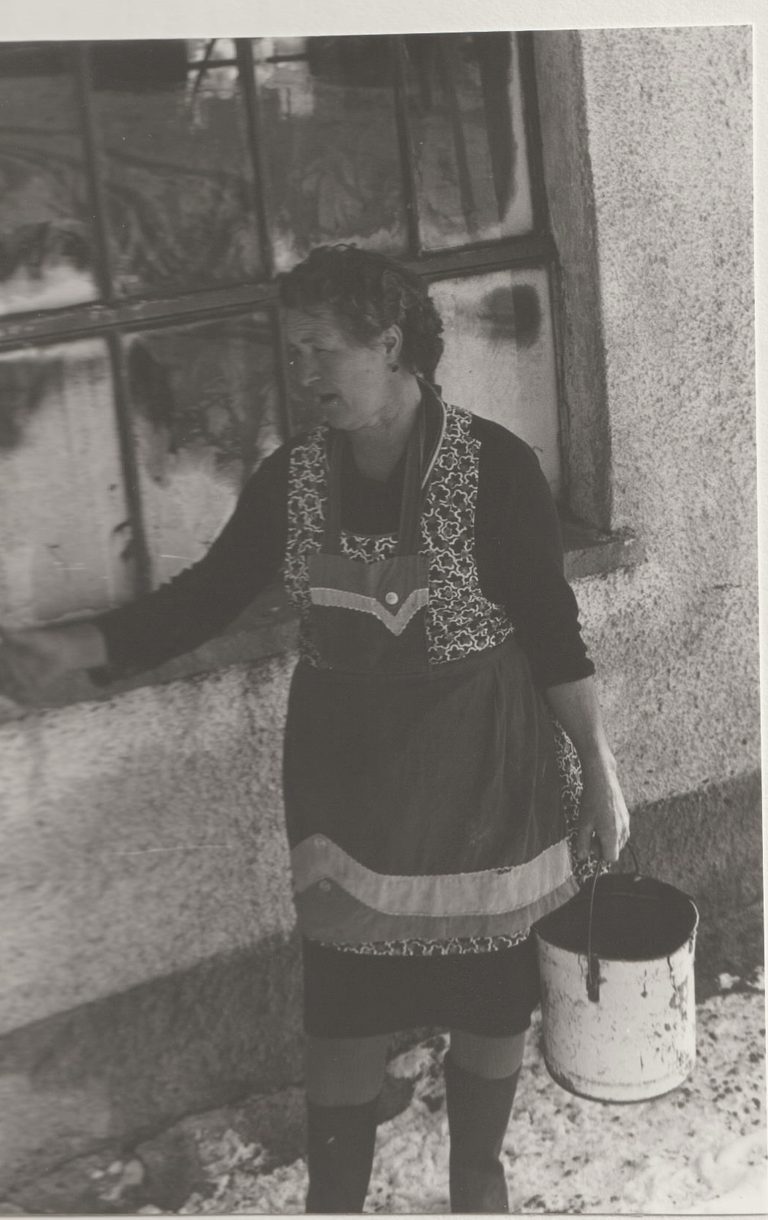 Historische Aufnahme: Frau mit Futtereimer am Stall des Hofs Kilger